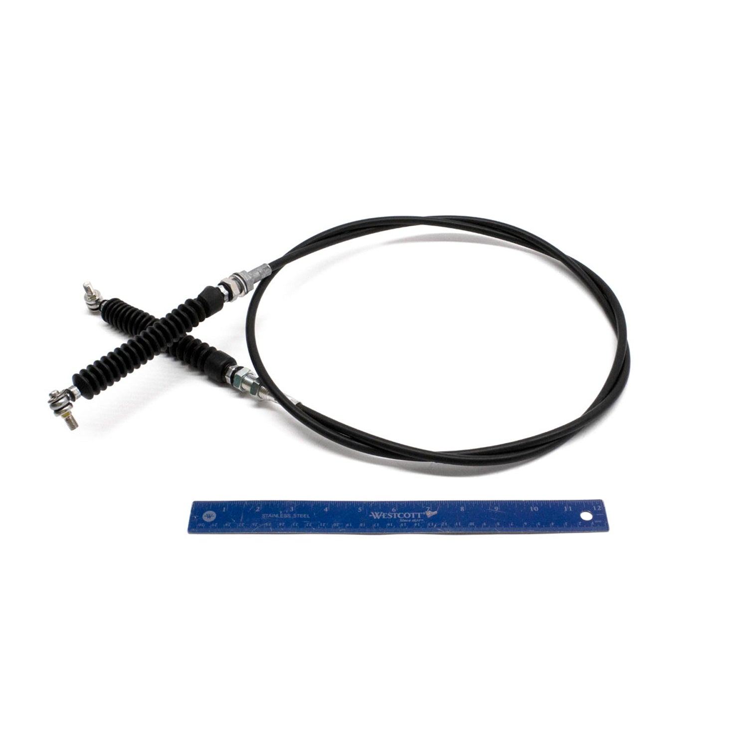 Black flexible shift cable with metal ends and protective rubber boots, shown next to a blue ruler for scale.