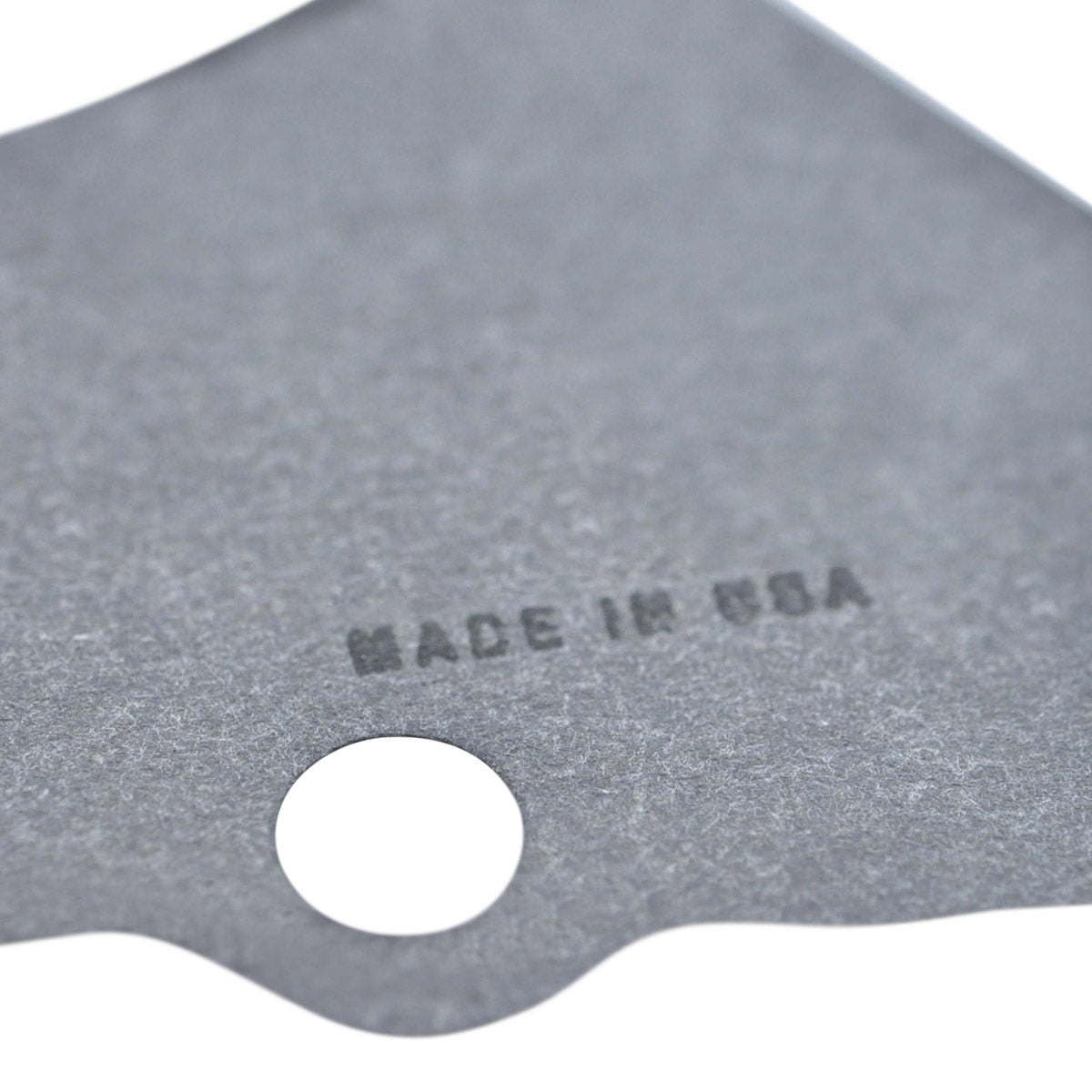 Gray triangular-shaped stator crankcase cover gasket with a circular bolt hole and "Made in USA" text printed on the surface.