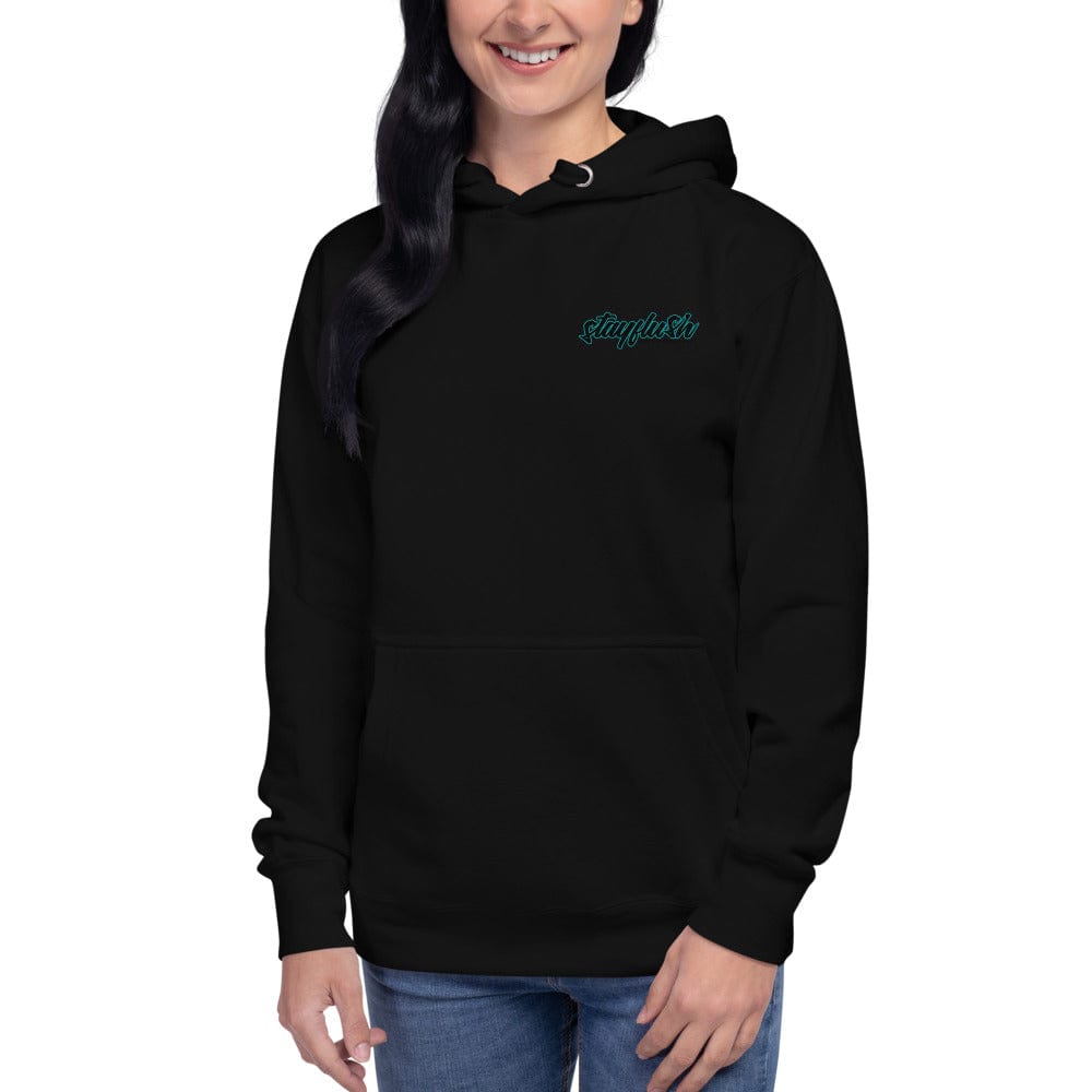 A person wearing a StayFlush Hoodie by StayFlush, 100% cotton and black with staytistic embroidered in blue-green on the upper left chest, paired with blue jeans—standing and smiling, perfect for riding season.
